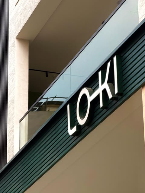 White dimensional LO-KI letters on a dark green slatted facade.